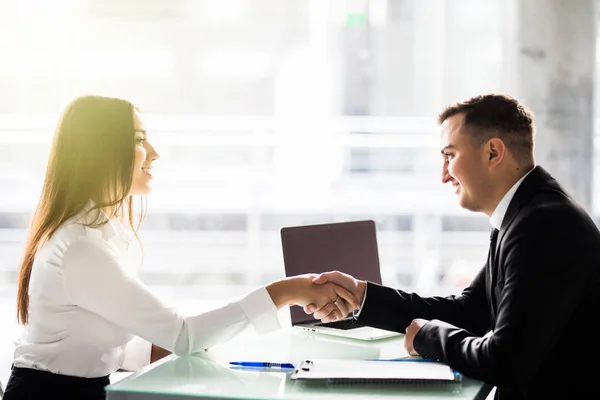 Vista lateral de los socios hombres y mujeres estrechando las manos sobre la mesa, manteniendo contacto visual, empresarios confiados listos para negociaciones efectivas, entrando en una asociación . — Foto de Stock