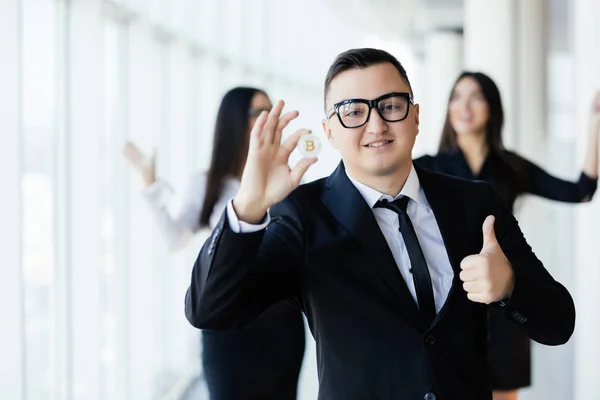 Blockchain and investment concept. Business man leader with thumbs up holding bitcoin in front of his team with raised hands on office. — Stock Photo, Image