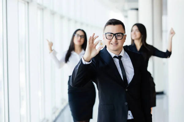 Blockchain and investment concept. Business man leader holding bitcoin in front of his team with raised hands on office. — Stock Photo, Image