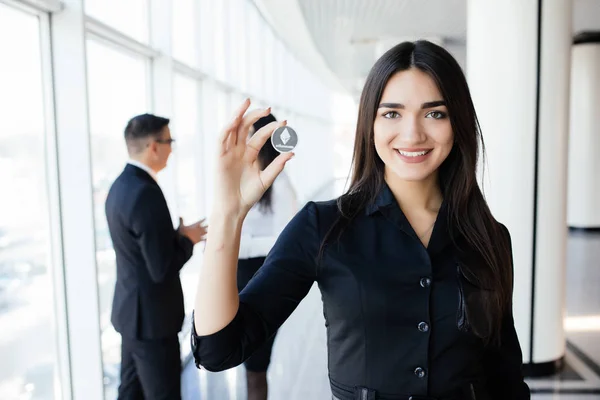 Blockchain y concepto de inversión. Líder mujer de negocios sosteniendo litecoin frente a su equipo con las manos en alto en la oficina . — Foto de Stock