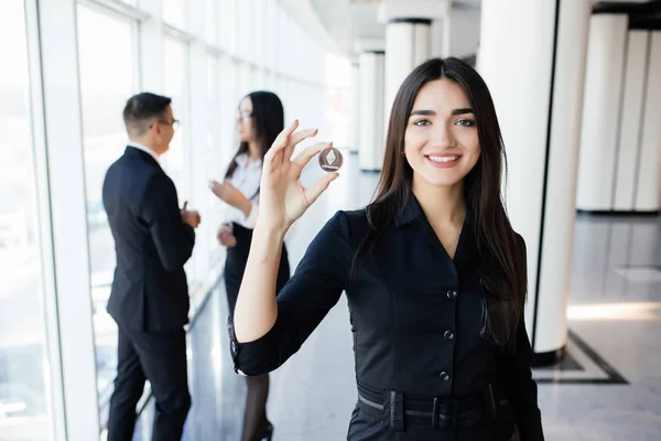 Blockchain y concepto de inversión. Líder mujer de negocios sosteniendo litecoin frente a su equipo con las manos en alto en la oficina . — Foto de Stock