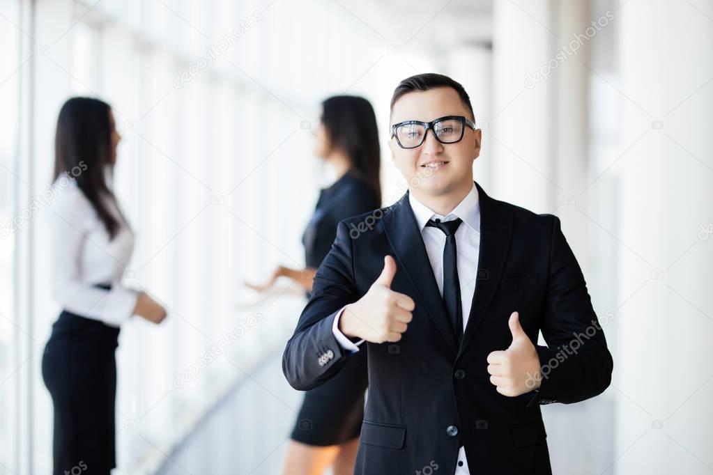 Group of business people with leader with thumbs up at front in office