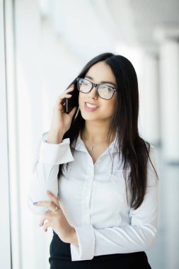 Gözlük güzellik kadın konuşmak panoramik pencerelere yakınındaki telefonda.