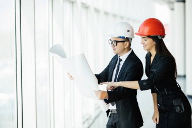 Erkek ve kadın bir kask içinde proje planı binanın içinde tutun. İnşaat iş.