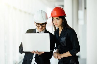 Kadın ve erkek girişimci ve hemlet toplantı, laptop planları binasında arıyorum iş, mimar