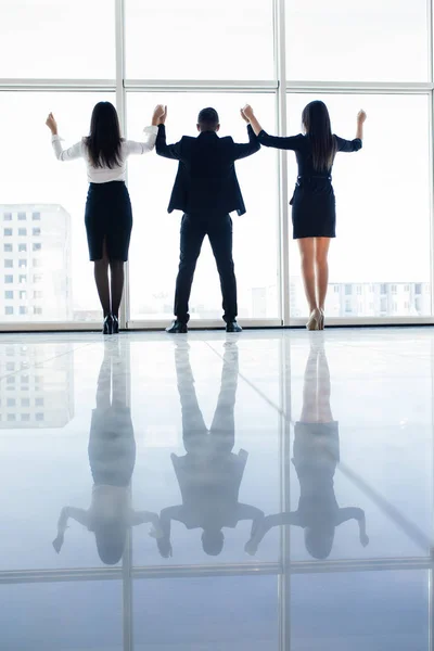 Business people raised hands in office team satisfied with result, won profitable contract, group of winners celebrate victory or great success against windows. — Stock Photo, Image
