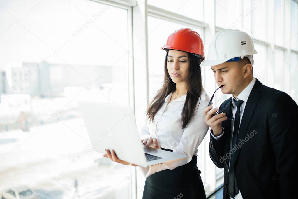 Engineering and architecture concept. Engineers working on a building site holding laptop, architect man working with engineer woman inspection in workplace for architectural plan