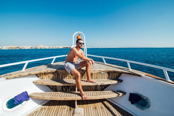 Красивый мужчина на яхте летом. Отдых на яхте, сидит на палубе яхты — стоковое фото