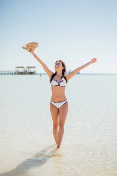 Летние каникулы счастье беззаботной радостной женщины шляпу солнца с распростертыми объятиями в успехе наслаждаясь тропическим пляжем назначения. Отдых в бикини на морском пляже — стоковое фото