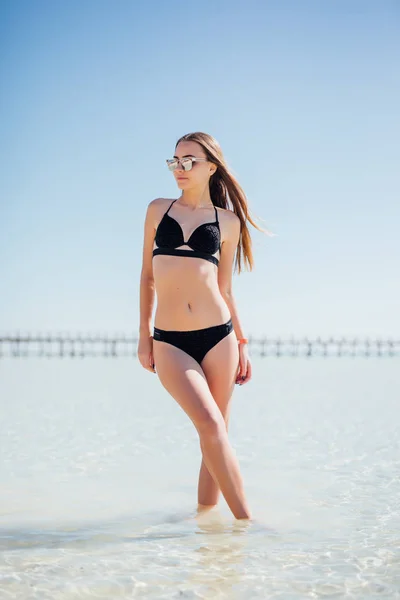 우아한 해변 여자 블랙 비치웨어, 여름 휴가 기간 동안 태양 열 대 목적지에 바다를 즐기는 선글라스에에서 비키니에 — 스톡 사진