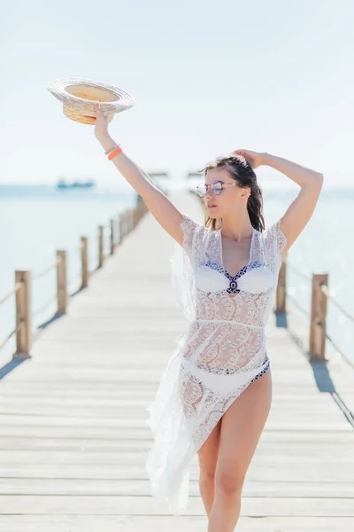 Lány pózol tengeri pier szalma kalap és napszemüveg. Szexi fürdőruha trópusi tengerparton napos kék égen nő. Nyári vakáció. Szabadidő, a tevékenység, a szabadidős koncepció. — Stock Fotó