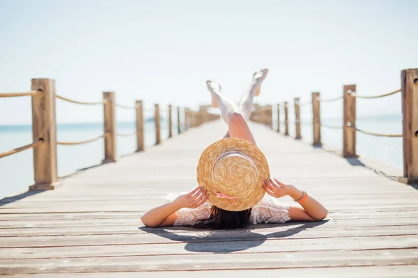 Primer plano retrato de mujer atractiva en bikini negro tomando el sol tumbado en el muelle de madera en el mar. Vocación de verano — Foto de Stock