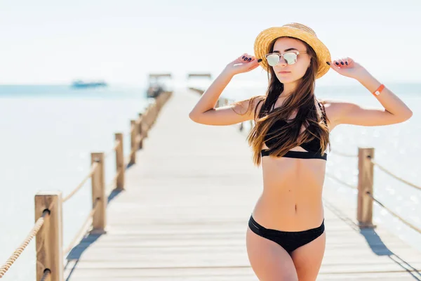 Conceito de moda de férias de verão - mulher bronzeadora usando chapéu de sol no mar em um cais de madeira — Fotografia de Stock