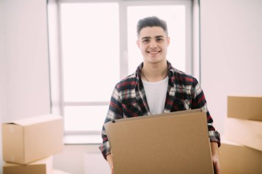 Yeni ev kutularına taşıyan gülümseyen bir adam portresi. Yer değiştirme ve taşıma.