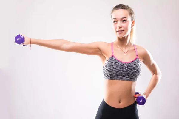 Ritratto di giovane donna felice sorridente in abbigliamento sportivo, facendo esercizio di fitness con manubri su sfondo bianco — Foto Stock