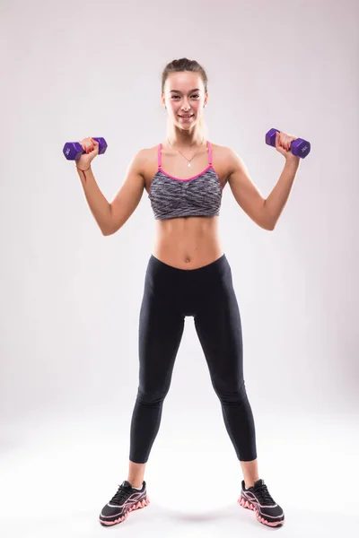 Ritratto di giovane donna felice sorridente in abbigliamento sportivo, facendo esercizio di fitness con manubri su sfondo bianco — Foto Stock