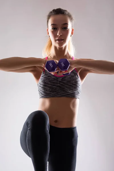 Porträt einer jungen glücklich lächelnden Frau in Sportbekleidung, die Fitnessübungen mit der Hantel vor weißem Hintergrund macht — Stockfoto