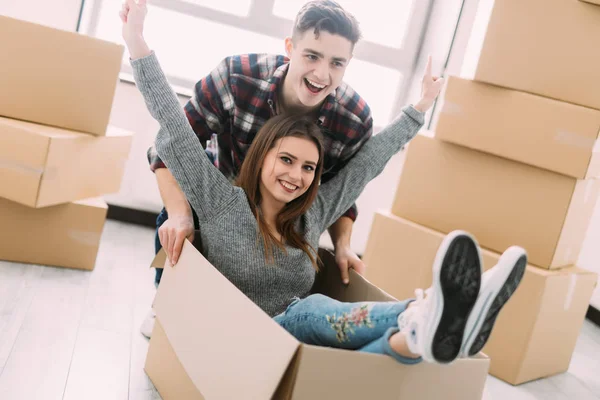 Glada unga leende par ha kul med pappkartonger i nya hus på flyttdagen. — Stockfoto