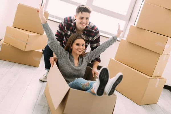 Glada unga leende par ha kul med pappkartonger i nya hus på flyttdagen. — Stockfoto