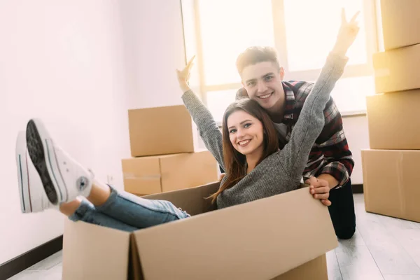Glada unga par har kul med pappkartonger i nya hus på flyttdagen. — Stockfoto