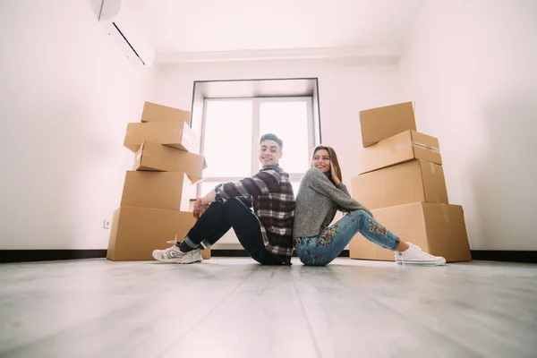 Unga par som flyttar i nya hem. Par sitter på golvet och avkopplande efter rengöring och uppackning i ny lägenhet — Stockfoto