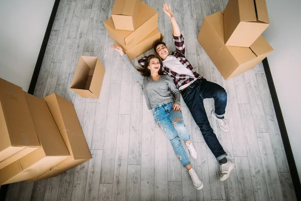 Det lyckliga unga paret låg på golvet nära kartong lådor. Visa från ovan — Stockfoto