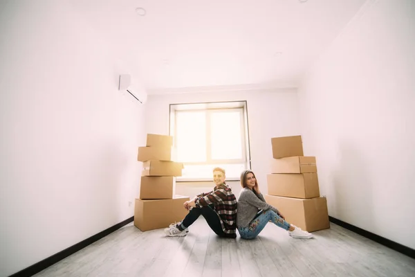 Jong koppel bewegen in nieuwe huis. Paar zittend op de vloer en ontspannen na het schoonmaken en uitpakken in nieuwe appartement — Stockfoto