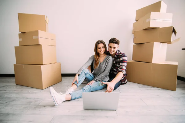 Unga lyckliga paret söker lägenheter med laptop. Rörliga, köp av ny bostad. — Stockfoto
