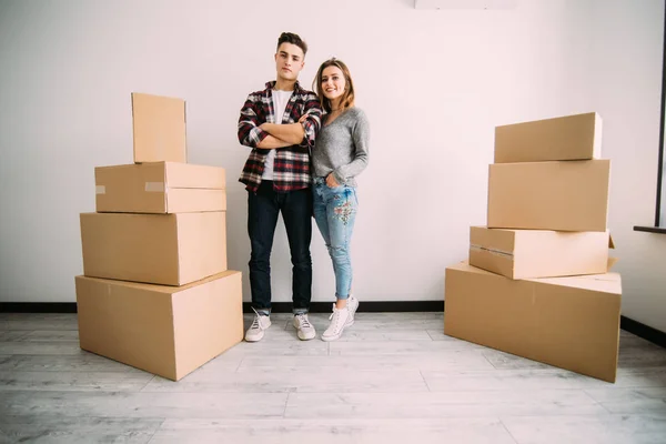 幸福的情侣站在他们的新公寓的盒子附近。搬迁和搬家. — 图库照片