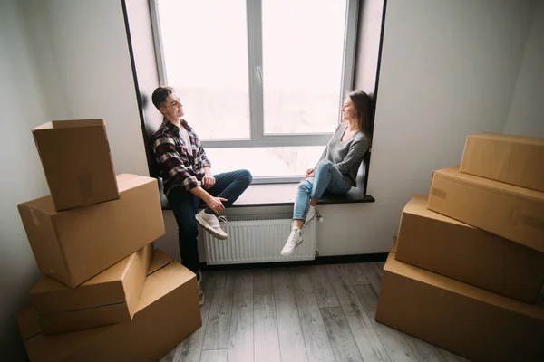 Couple emménageant dans la maison assis sur le rebord de la fenêtre. Couple emménageant dans une nouvelle hause. Réinstallation . — Photo