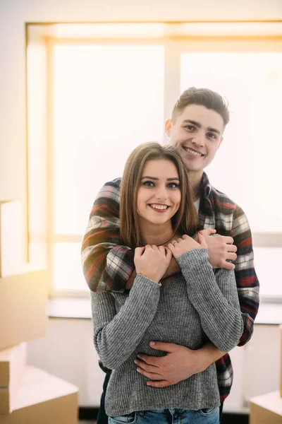 Bonito casal abraçando e sorrindo em sua nova casa. Mudando para um novo aparato . — Fotografia de Stock