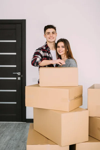 Улыбающаяся пара, опирающаяся на коробки в новом доме. Пара в новом аппарате после переезда . — стоковое фото