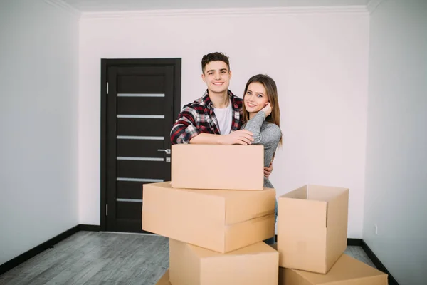 微笑的情侣倚在新家的箱子。年轻夫妇搬到一个新的公寓一起搬迁 — 图库照片