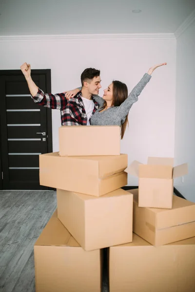 Glad och lycklig ung par seger höjde händerna på sitt nya hem med rörliga kartong under flytta in i ny lägenhet — Stockfoto