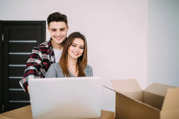 Par med laptop runt kartong lådor i nya lägenheten — Stockfoto