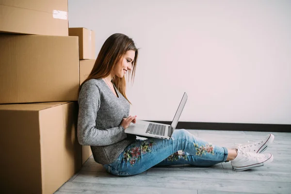 妇女坐在地板附近的一个箱子与笔记本电脑, 而移动到新的 hause — 图库照片