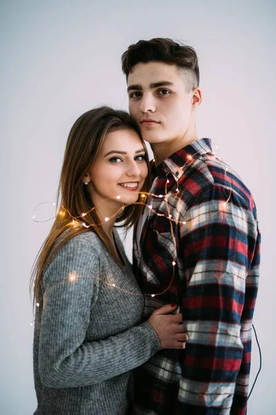 Jovem casal apaixonado abraçar uns aos outros com luzes no fundo branco — Fotografia de Stock