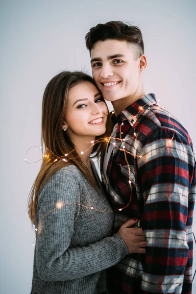 Jong koppel in liefde omhelzen elkaar met lampjes op de witte achtergrond — Stockfoto