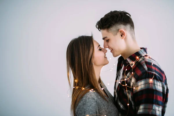 Jovem casal apaixonado abraçar uns aos outros com iluminação no pescoço no fundo branco — Fotografia de Stock