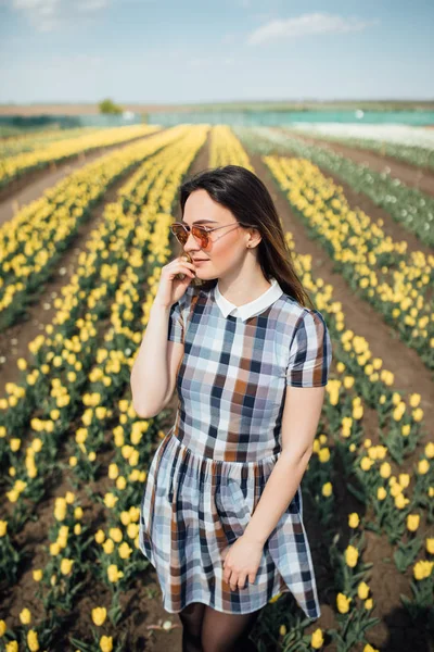 Beautiful happy woman in a field of yellow tulips smiling — Stock Photo, Image