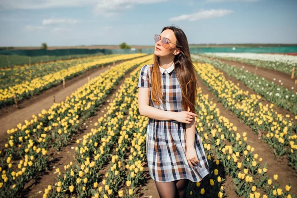 Girl with sunglasses posing in yellow tulip field — Stock Photo, Image