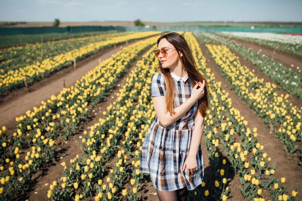 Красивая девушка в солнечных очках с тюльпанами на заднем плане — стоковое фото