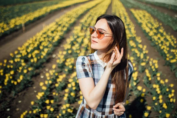 Bella ragazza in occhiali da sole con tulipani su sfondo — Foto Stock