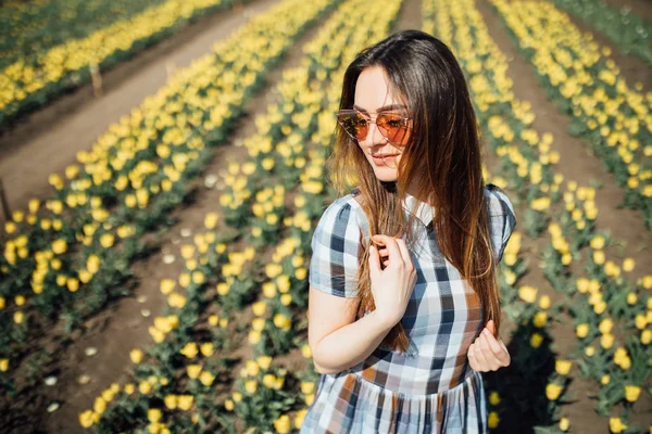Ragazza con occhiali da sole in posa in campo tulipano giallo — Foto Stock