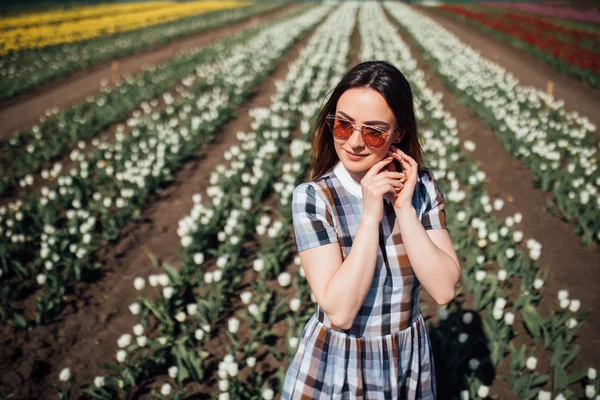 Giovane donna felice in occhiali da sole nel campo dei tulipani bianchi — Foto Stock