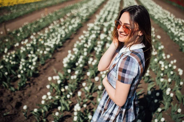 Giovane donna felice in occhiali da sole nel campo dei tulipani bianchi — Foto Stock