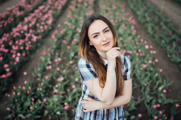 Bella donna felice in un campo di tulipani rosa sorridente e in posa — Foto Stock