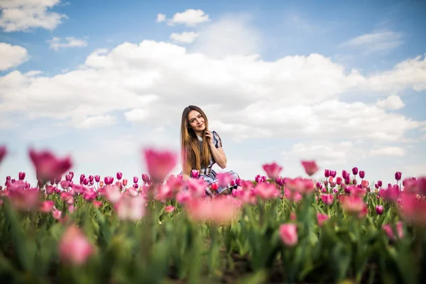 Bella donna felice in un campo di tulipani rosa su cielo blu su sfondo — Foto Stock