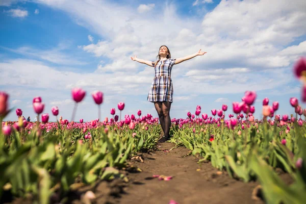 Bella donna felice in un campo di tulipani rosa su cielo blu su sfondo — Foto Stock