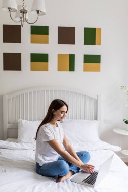 Yatakta yatarken dizüstü bilgisayar kullanan kadın. Notebook klavye, Online çalışma evde kamera gülümseyen yazarak mutlu güzel kız closeup portresi.